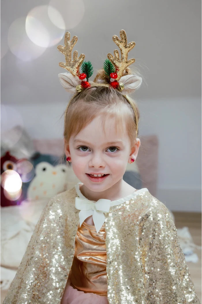 Girl wearing gold glitter reindeer antler headband with holly and red berries