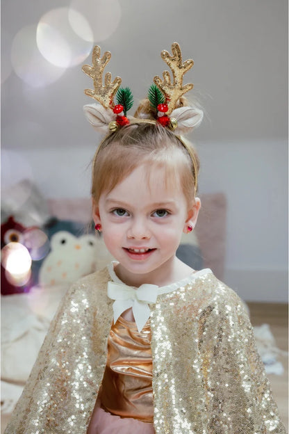 Girl wearing gold glitter reindeer antler headband with holly and red berries
