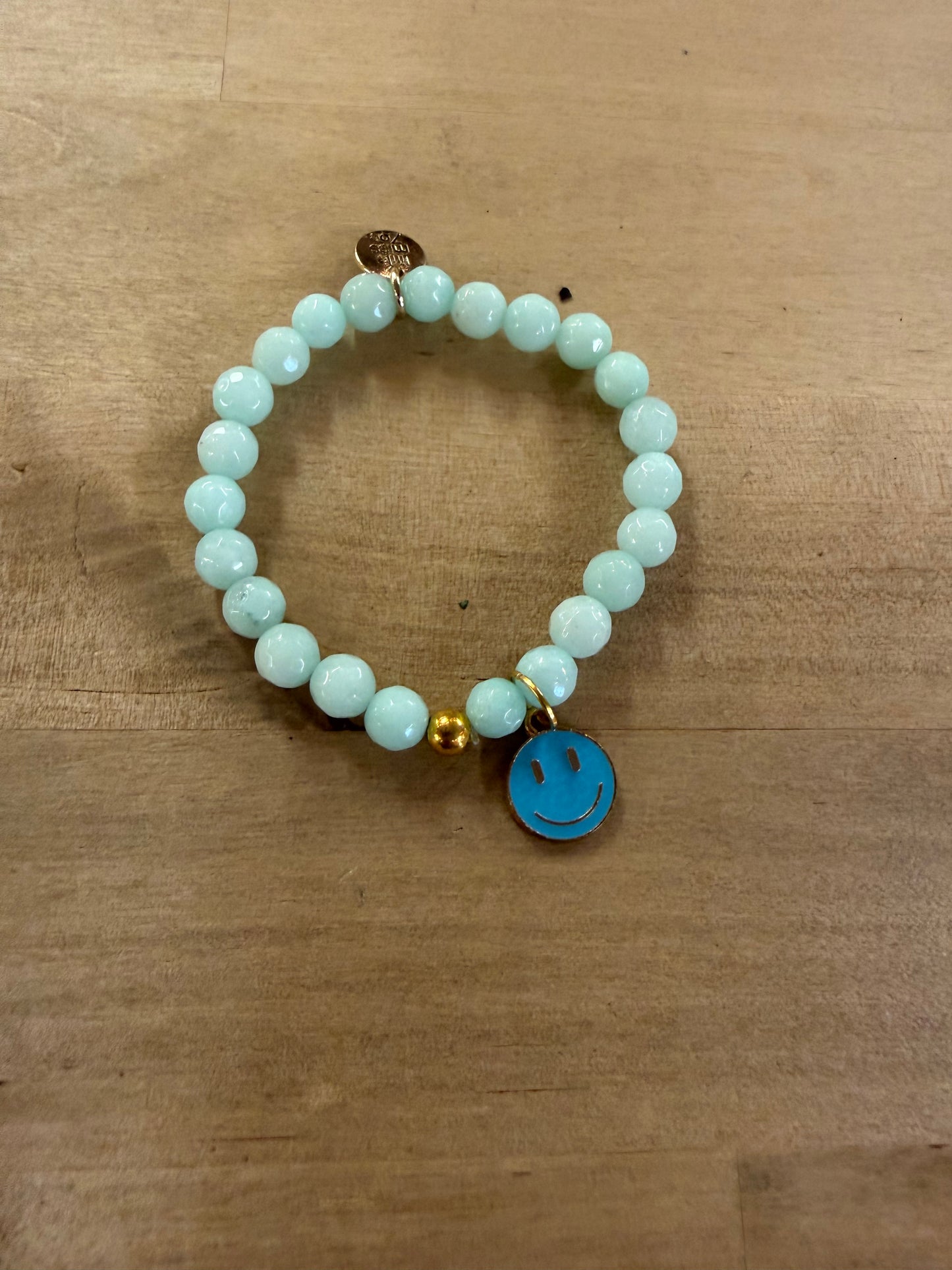 Light blue beaded stretch bracelet with a turquoise enamel smiley face charm