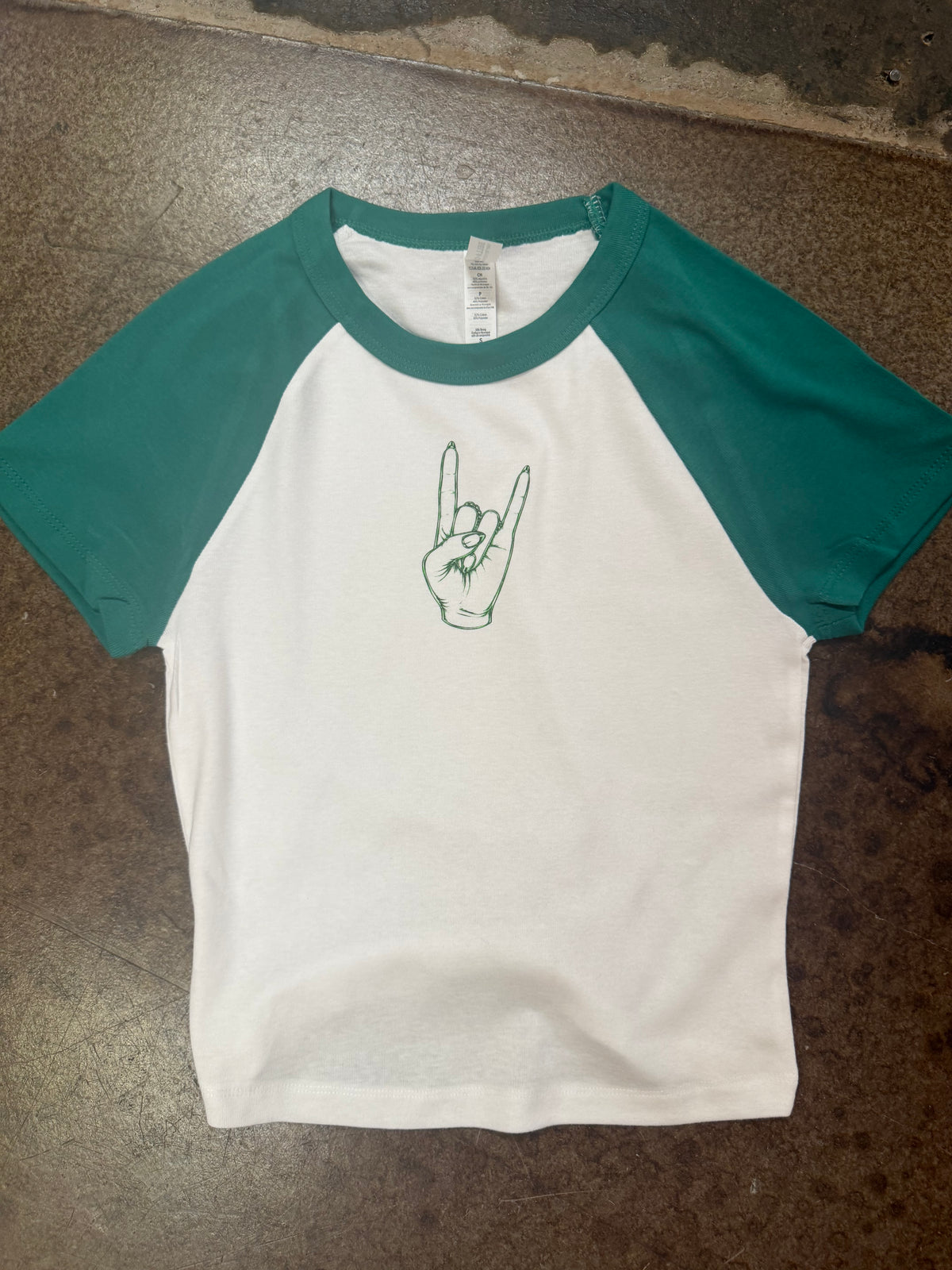 White raglan baby tee with teal sleeves and green rock hand graphic