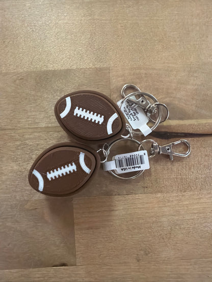 Two brown rubber football keychains with white laces and silver swivel clips