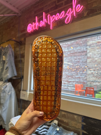 Amber translucent jelly sandal sole with bubble grid texture, held up in store