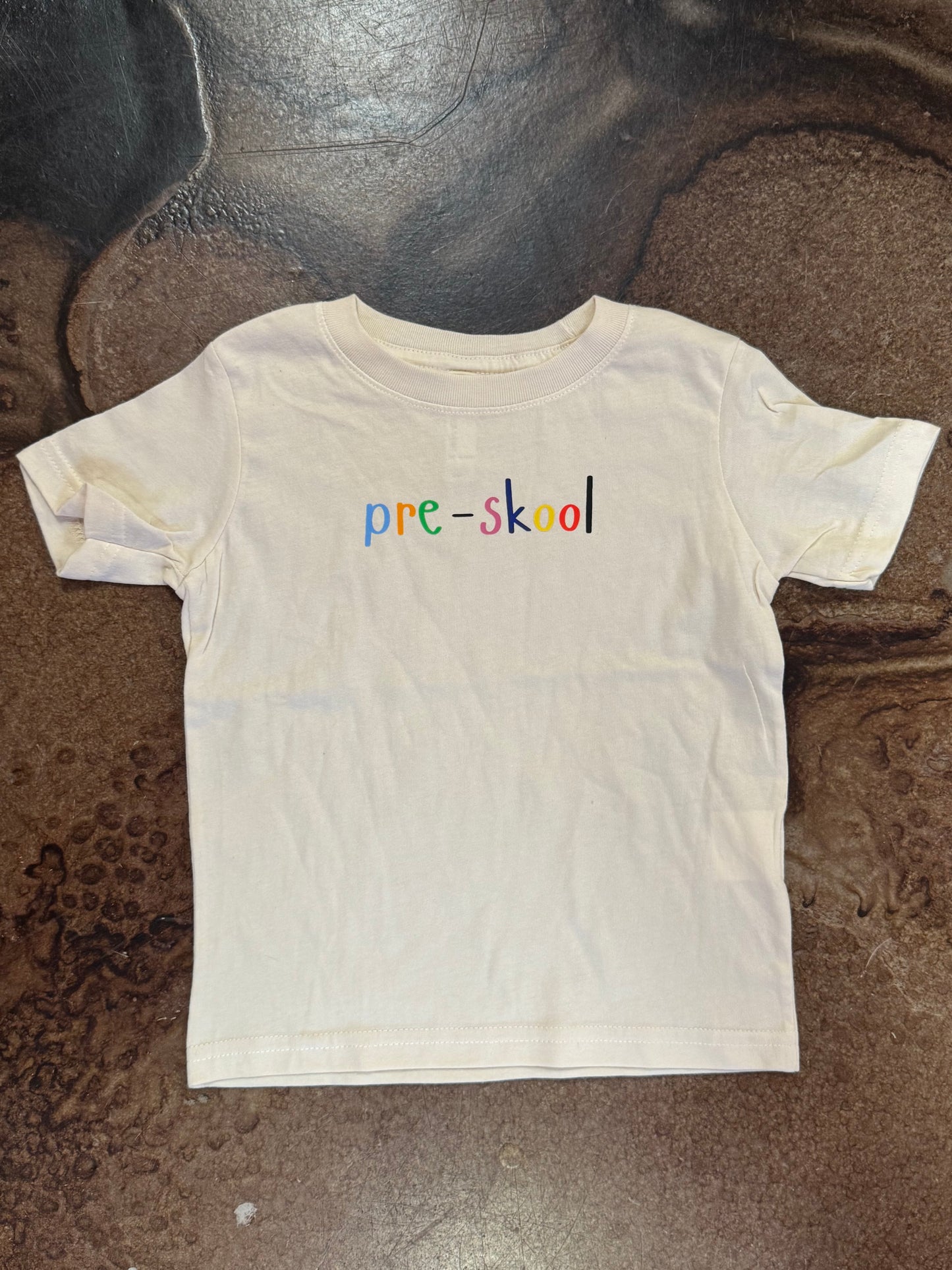 White kids' tee with colorful 'pre-skool' text on chest