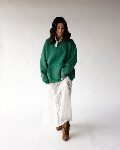 Oversized green hoodie styled with white lace midi skirt and brown cowboy boots