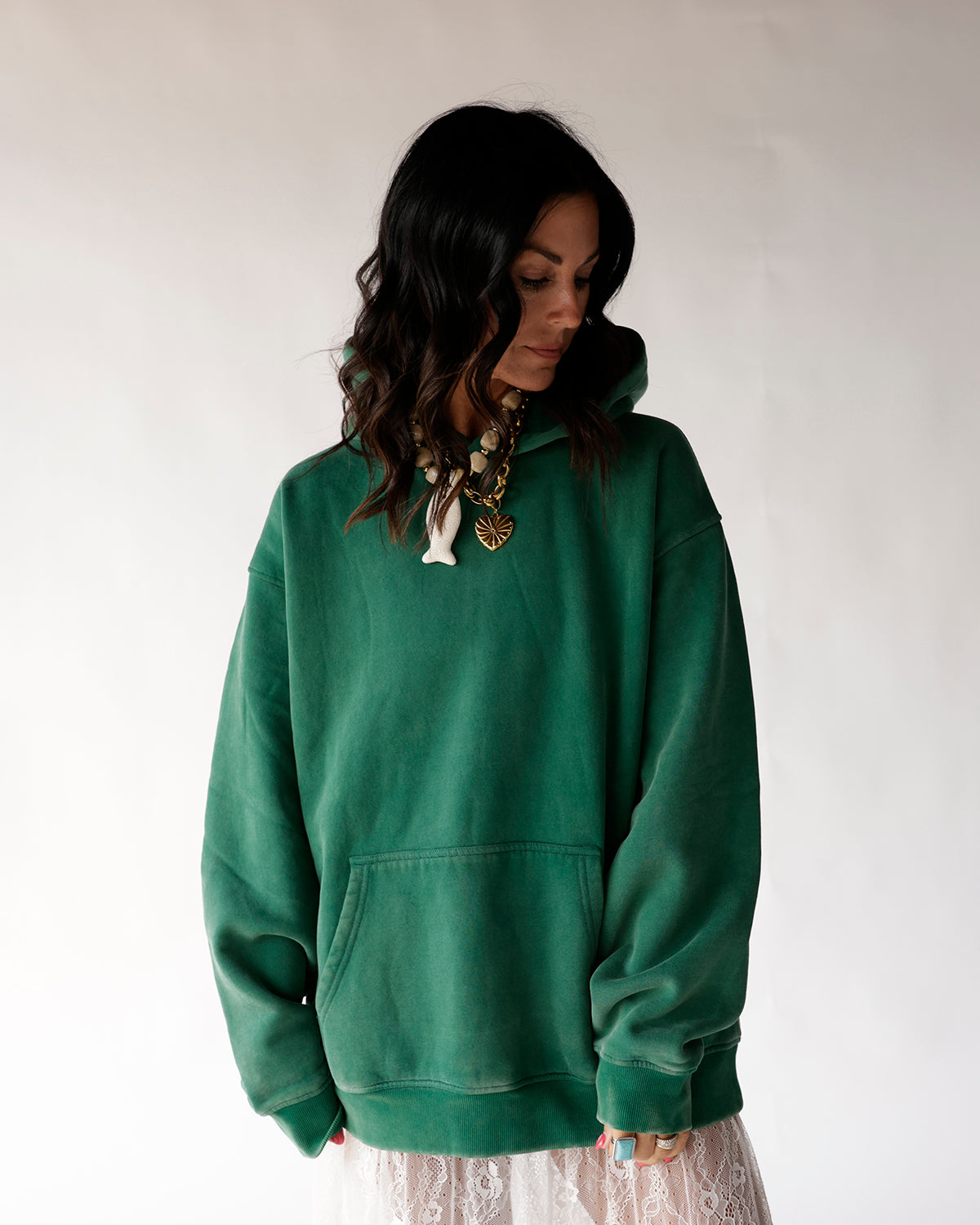 Oversized green pullover hoodie with front kangaroo pocket, worn with lace skirt