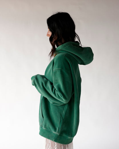 Oversized green fleece hoodie shown from side angle on dark-haired model
