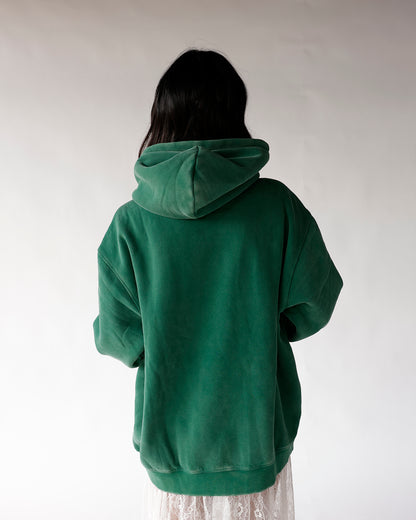 Back view of oversized green fleece hoodie with hood up, worn over lace skirt