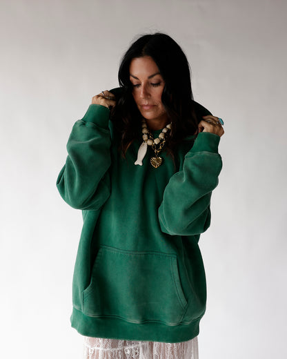 Oversized green pullover hoodie with front pocket, worn over white lace skirt