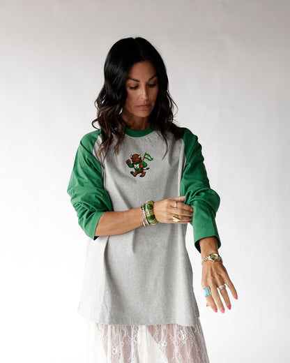 Gray and green raglan long sleeve tee with mascot graphic, worn by woman