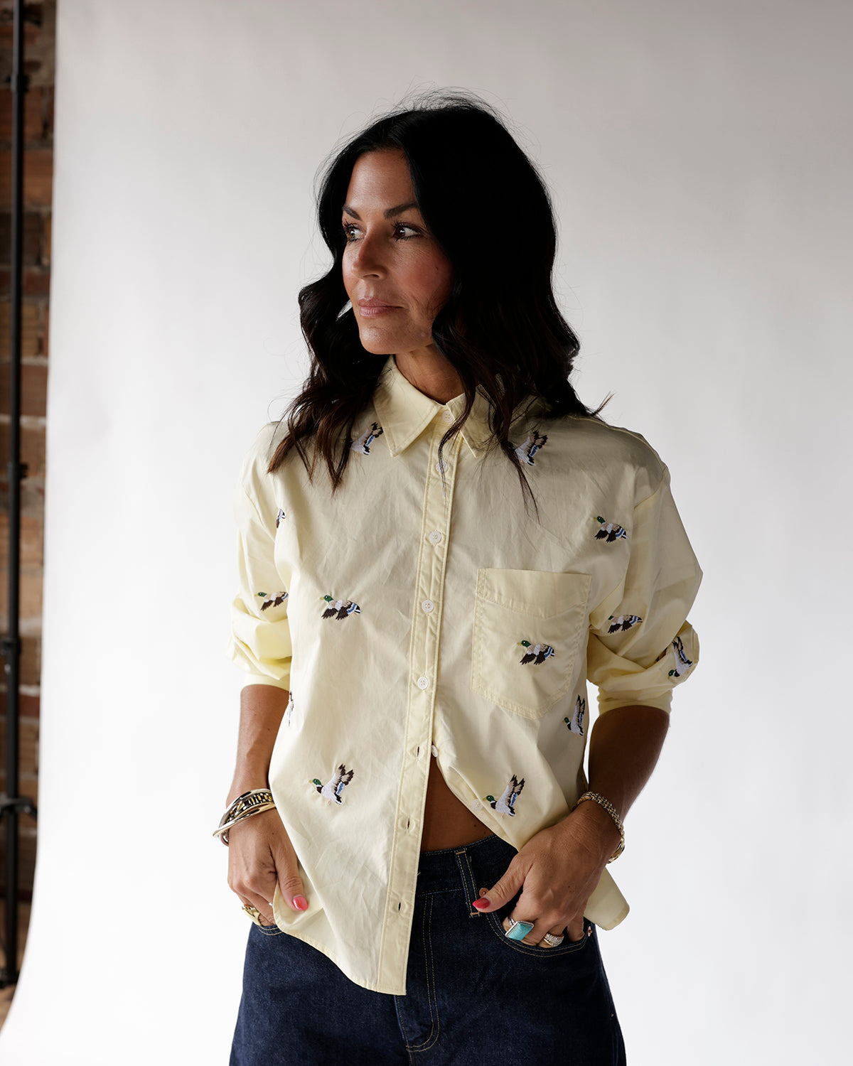 Light yellow button-up shirt with embroidered duck pattern, worn with dark jeans