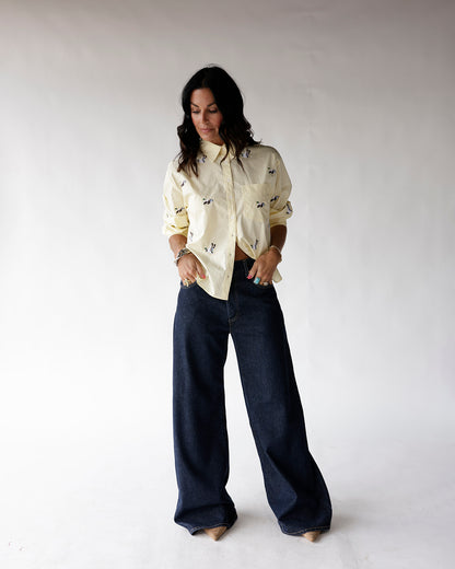 Light yellow button-up shirt with small duck print, worn with wide-leg dark jeans