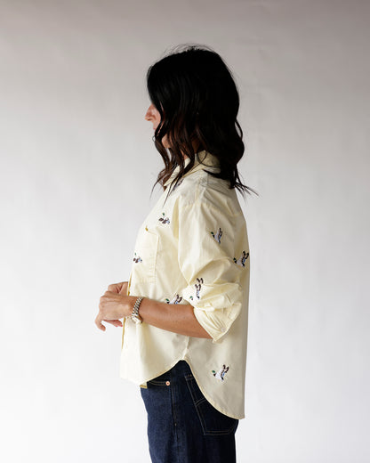 Light yellow button-up shirt with duck print, rolled sleeves, worn with dark jeans
