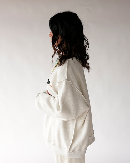 Oversized cream mock neck sweatshirt with duck graphic, side profile view