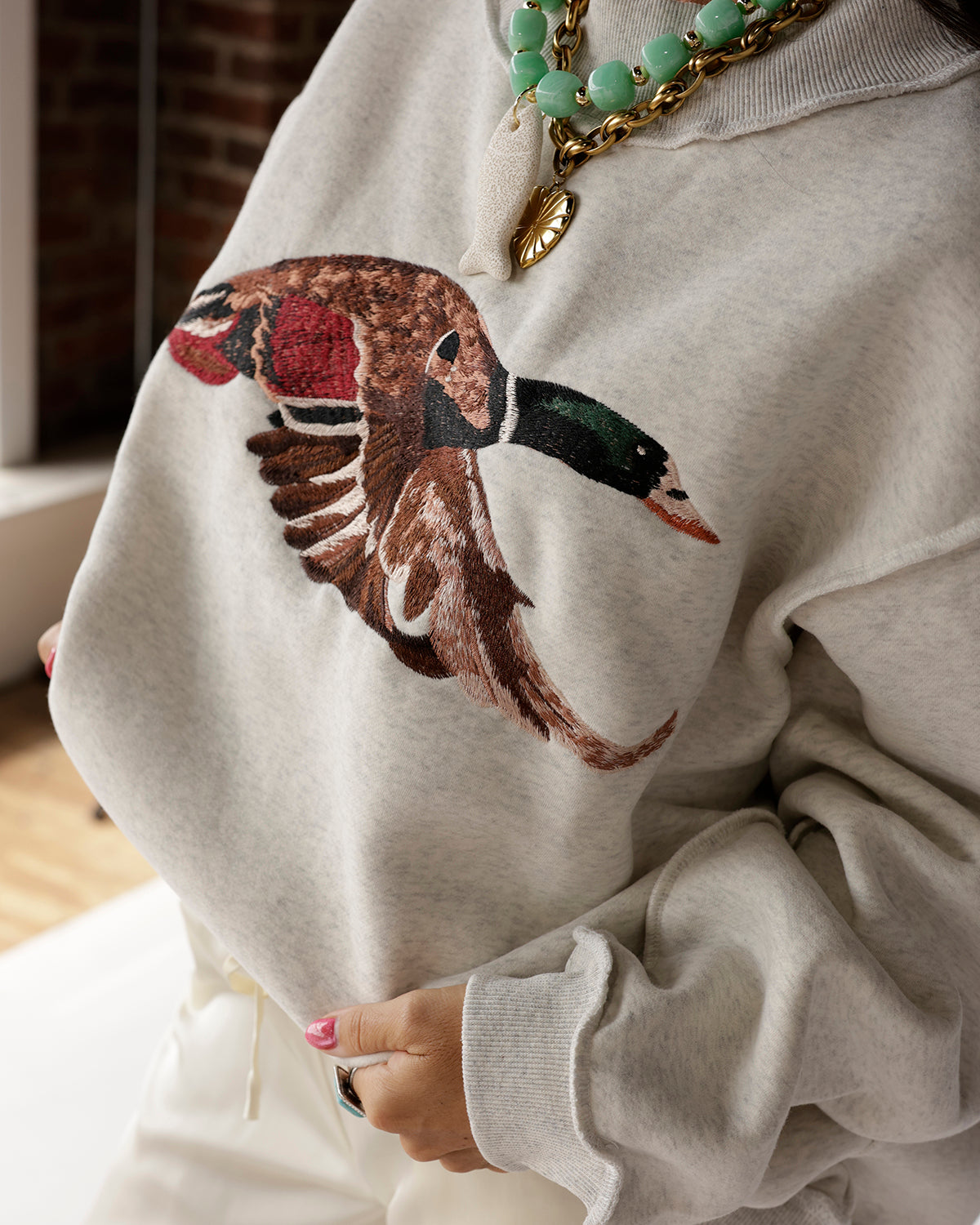 Oatmeal mock neck sweatshirt with embroidered flying mallard duck graphic on chest