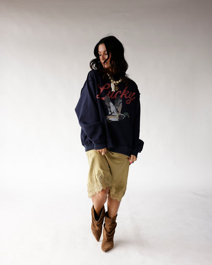 Oversized navy sweatshirt with Lucky script and mallard duck graphic, worn with satin skirt