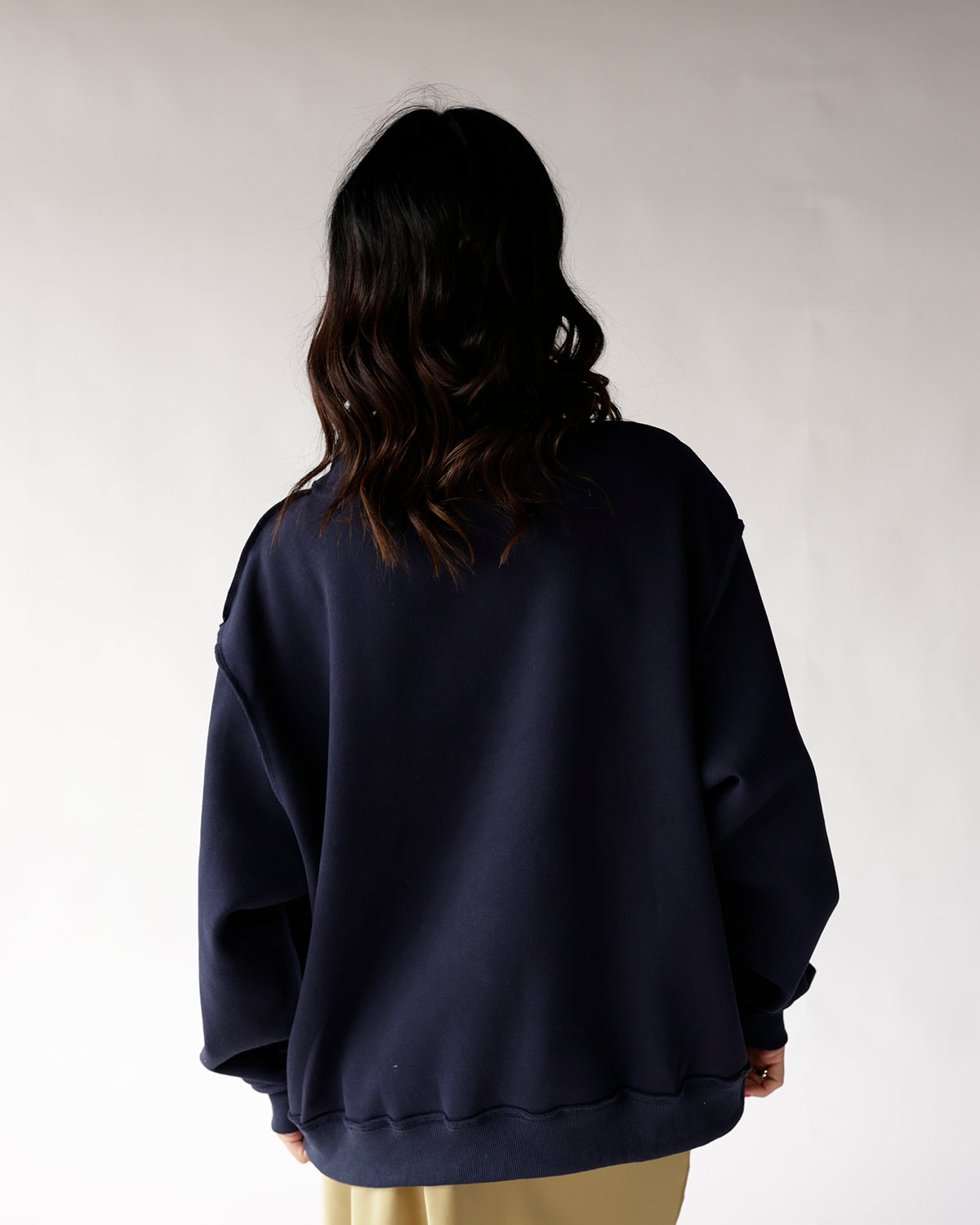 Oversized navy blue crewneck sweatshirt shown from the back on a model