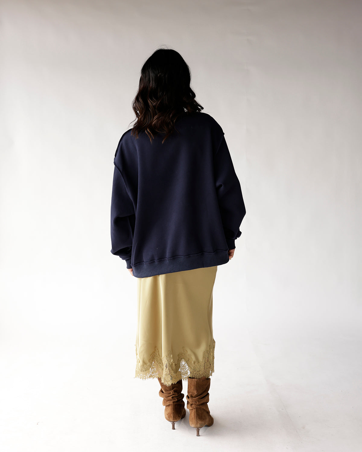Oversized navy blue crewneck sweatshirt worn from back view with lace midi skirt