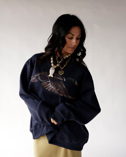 Oversized navy blue sweatshirt with mallard duck graphic, styled with layered necklaces