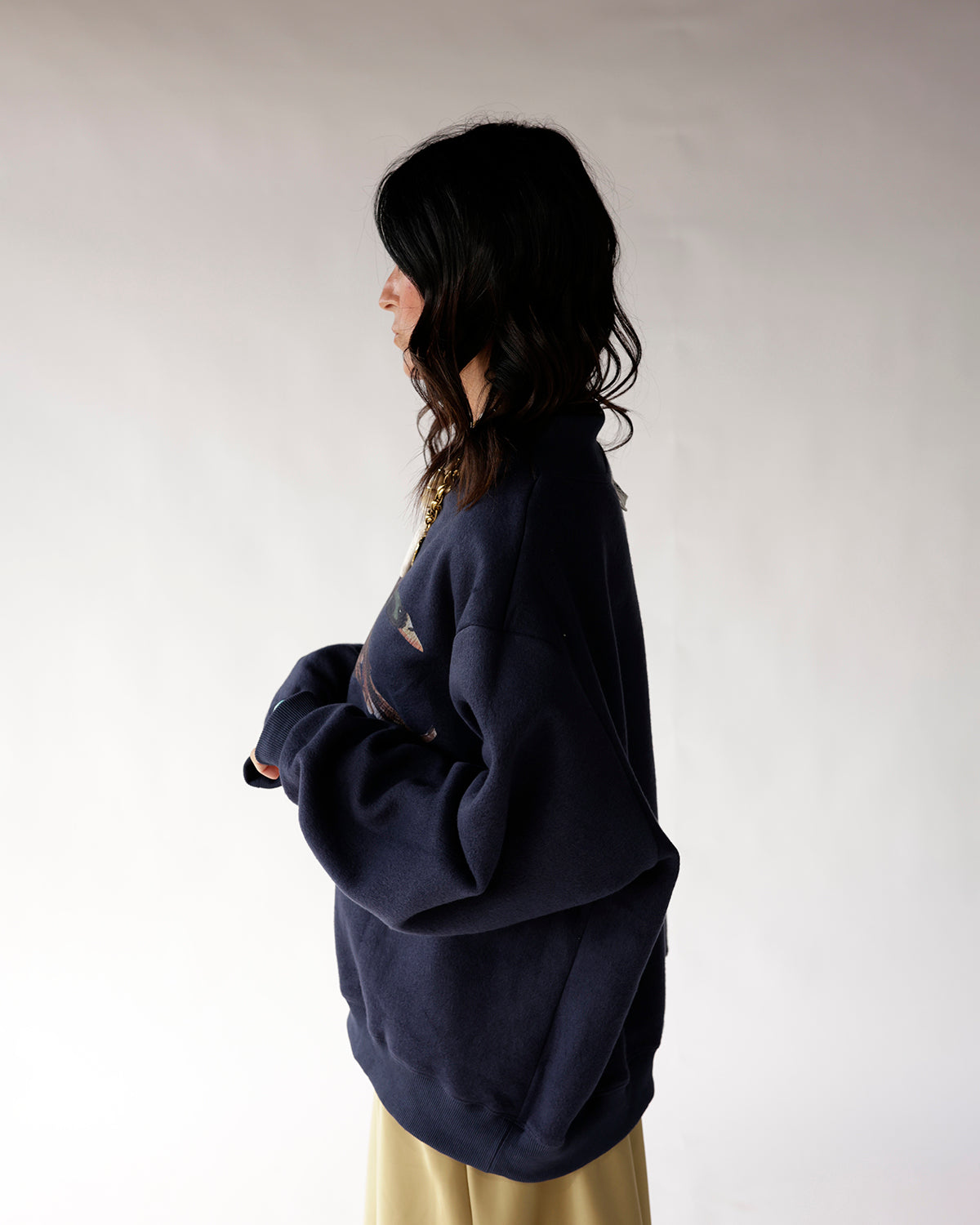 Oversized navy blue mock neck sweatshirt with graphic print, worn as side profile