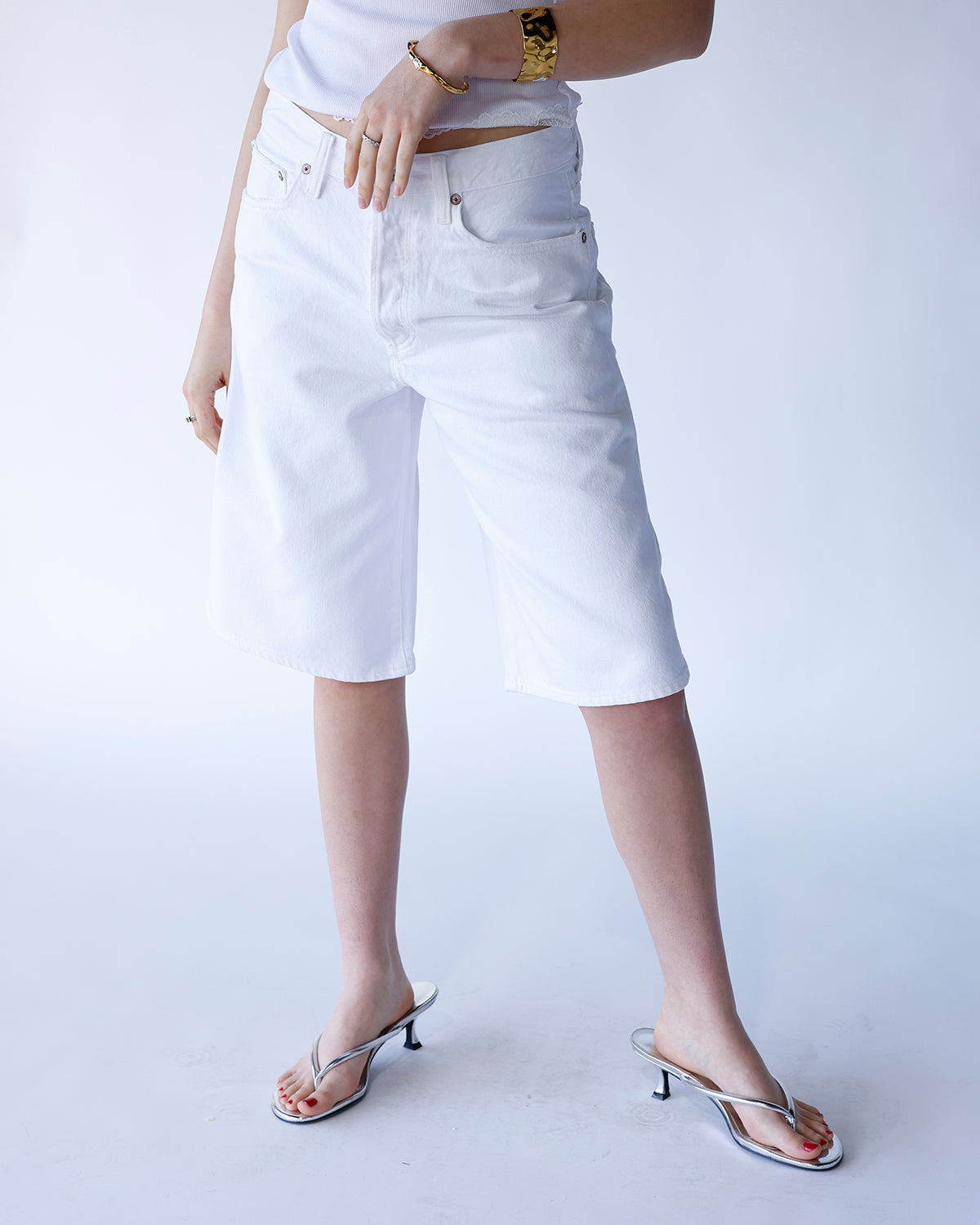 AGOLDE Ramona white denim longline shorts styled with silver kitten heel sandals