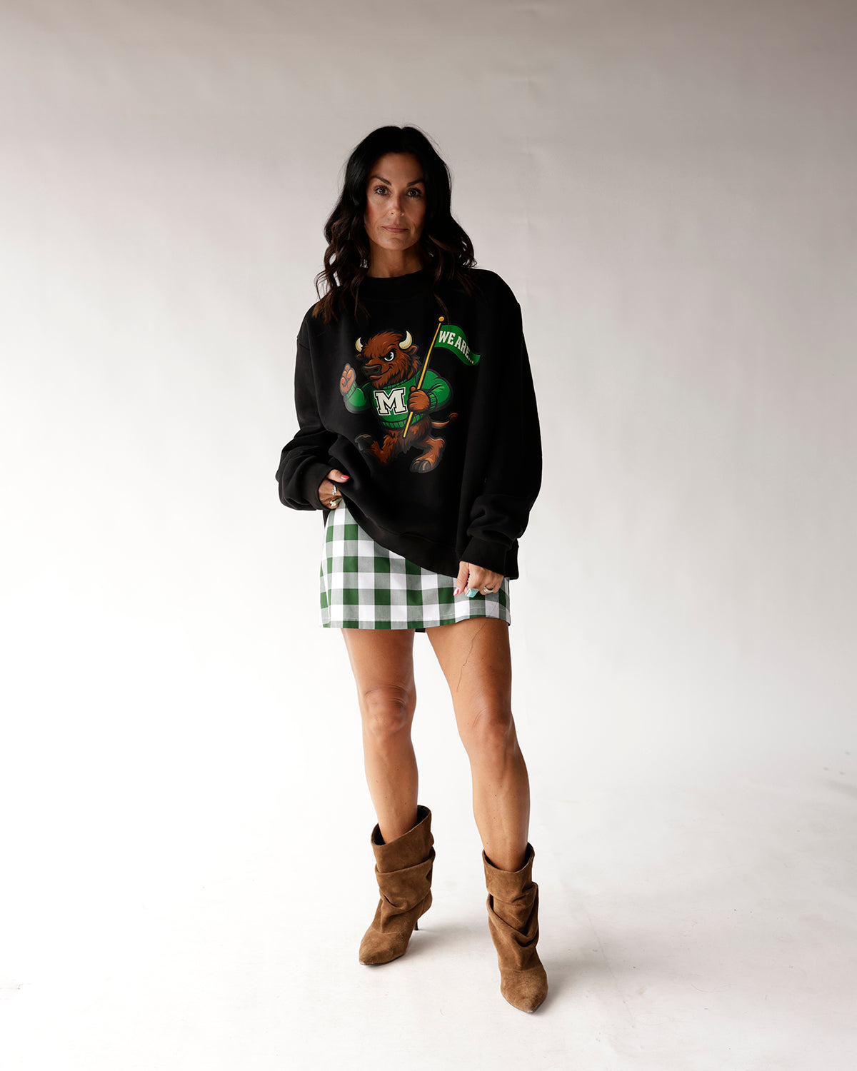 Black oversized sweatshirt with green bison mascot graphic, worn with plaid mini skirt