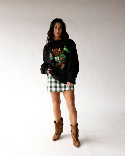 Black oversized sweatshirt with green bison mascot graphic, worn with plaid mini skirt