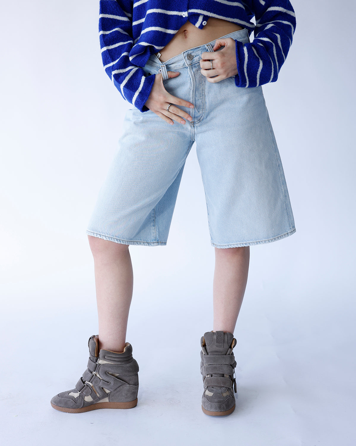 Light wash wide-leg denim shorts, knee-length, worn with blue striped crop top and gray wedge sneakers