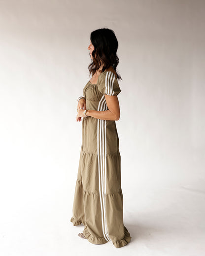 Olive green maxi dress with white racing stripes, puff sleeves, and tiered ruffle hem