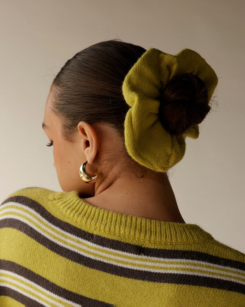 Yellow-green striped knit sweater styled with matching oversized scrunchie and gold hoop earring