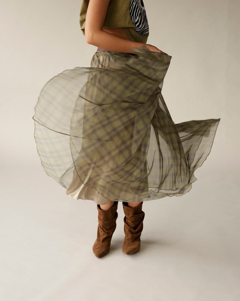 Olive green plaid organza maxi skirt mid-twirl, paired with tan suede boots.
