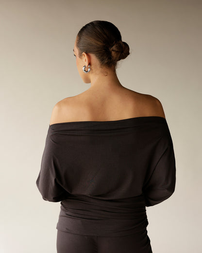 Black off-shoulder long sleeve top with draped batwing sleeves, back view