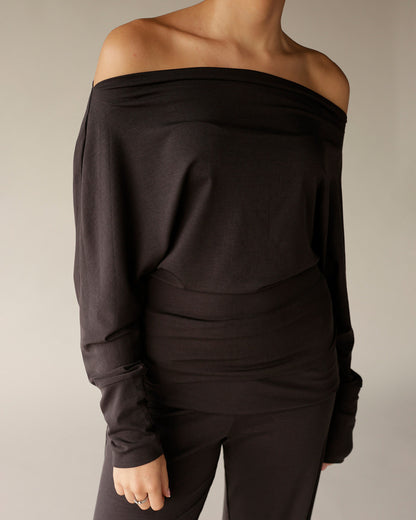 Black off-shoulder long sleeve top with draped neckline and relaxed fit