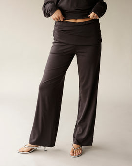 Dark brown wide-leg fold-over waist pants worn with silver strappy heels