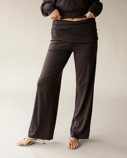 Dark brown wide-leg fold-over waist pants worn with silver strappy heels