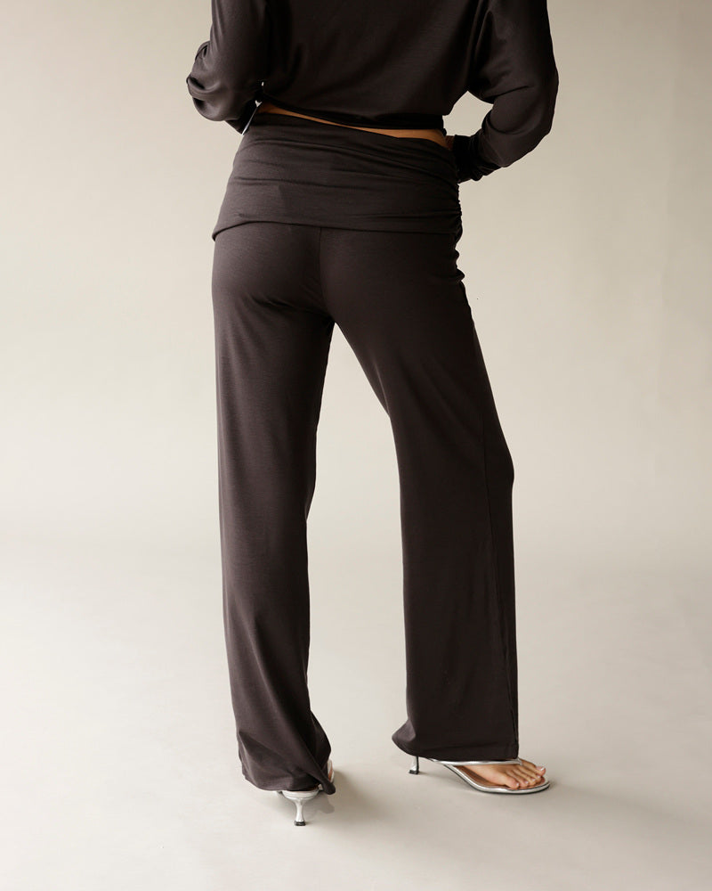 Dark brown wide-leg foldover waist pants with silver kitten heel sandals, back view
