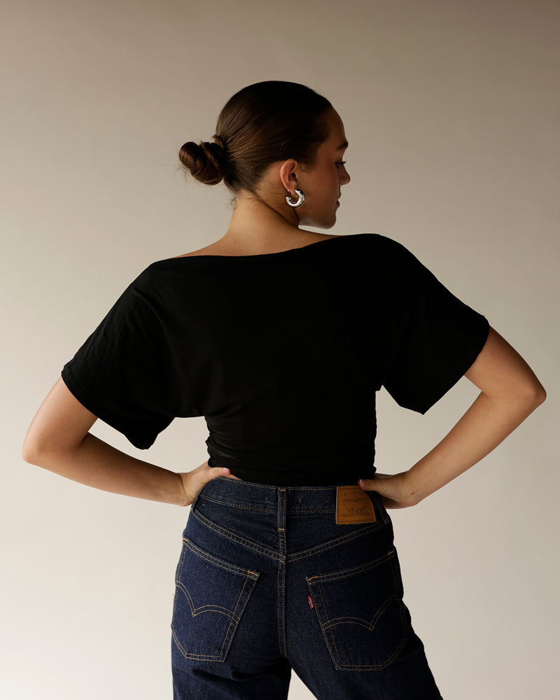 Dark navy high-waist Levi's straight leg jeans worn with black crop top, back view
