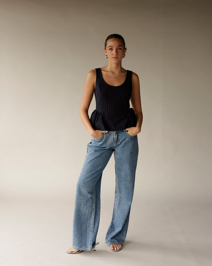 Navy pinstripe sleeveless peplum top with ruffled waist detail, worn with wide-leg jeans