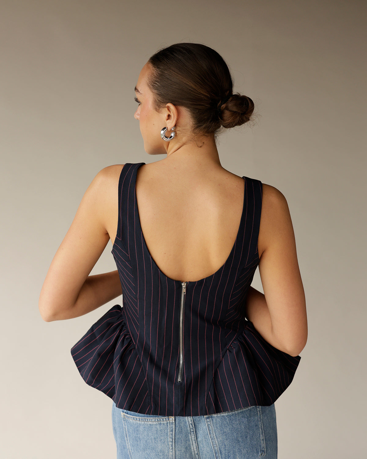Navy pinstripe sleeveless peplum top with open back, zipper, and red stripes