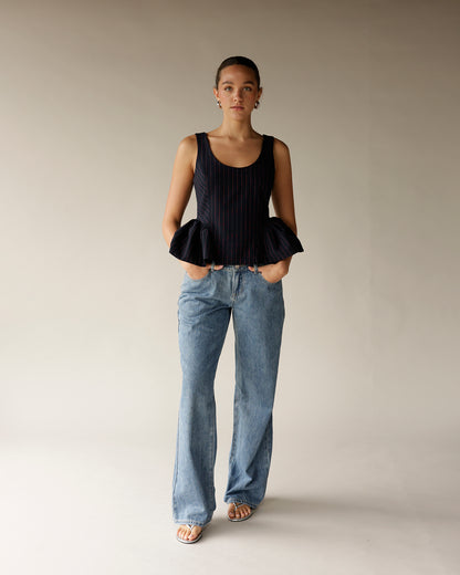Navy pinstripe sleeveless peplum top with ruffled hem, paired with wide-leg jeans