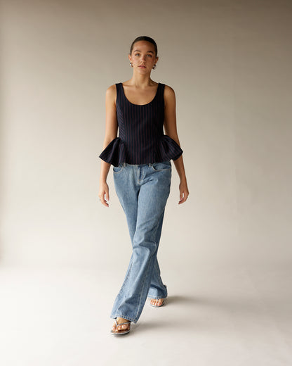 Navy pinstripe sleeveless peplum top with ruffled hem, paired with wide-leg jeans