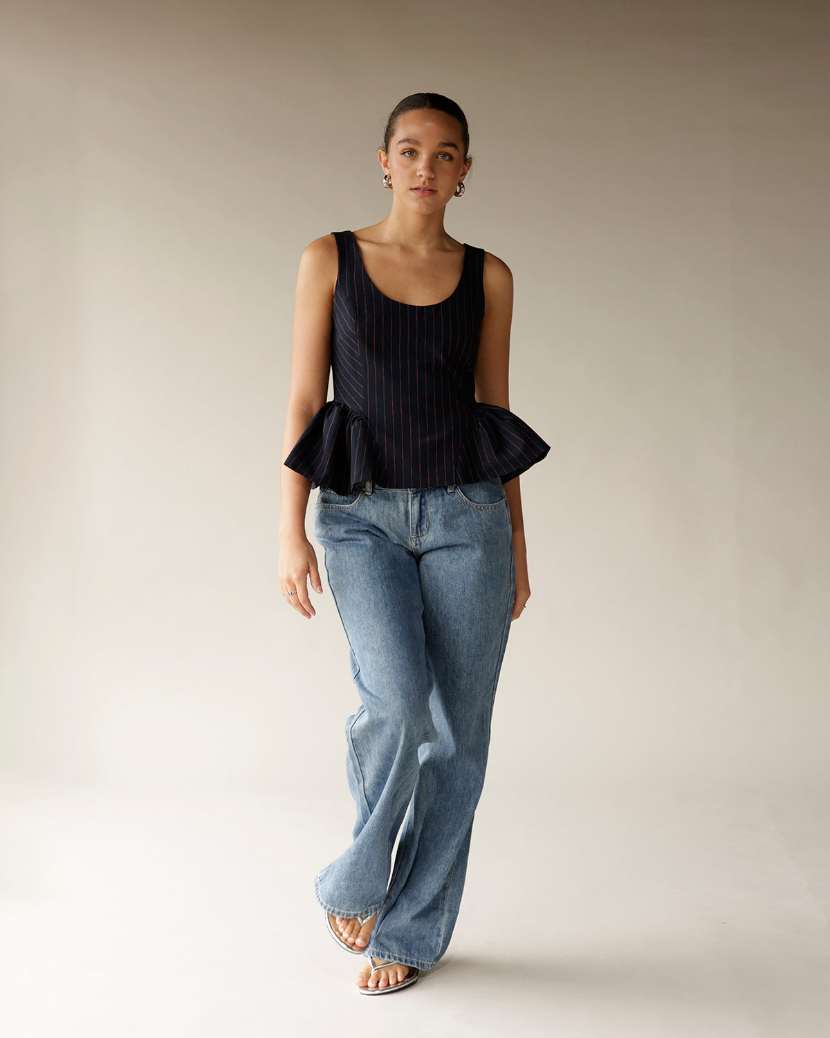 Navy pinstripe sleeveless peplum top with ruffle hem, styled with wide-leg jeans