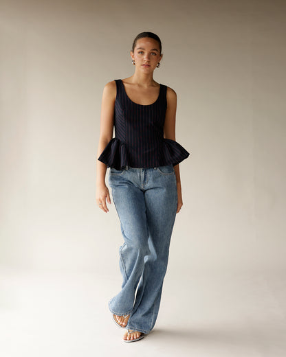 Navy pinstripe sleeveless peplum top with ruffle hem, styled with wide-leg jeans