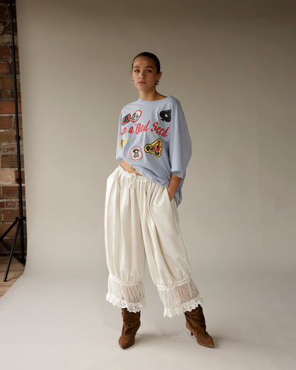 Cream satin wide-leg pants with lace trim hem and gathered waist detail