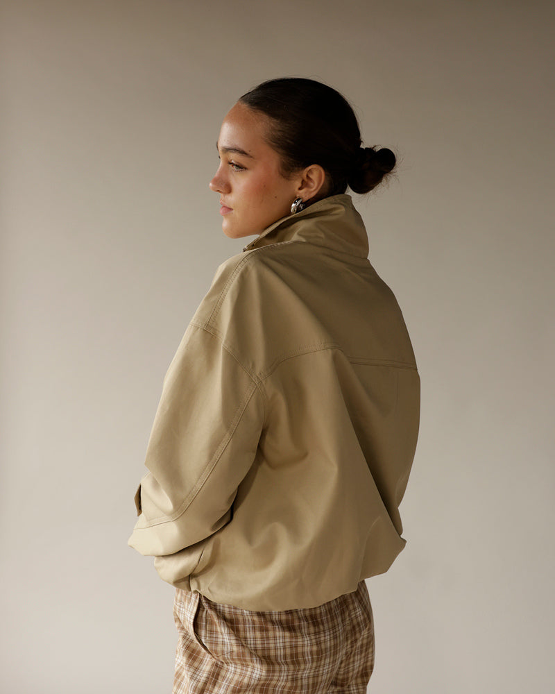 Women's oversized beige zip-up jacket with high collar, back view