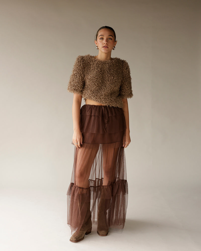 Women's brown fuzzy crop sweater with short sleeves, paired with sheer maxi skirt