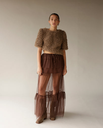 Women's brown fuzzy crop sweater with short sleeves, paired with sheer maxi skirt
