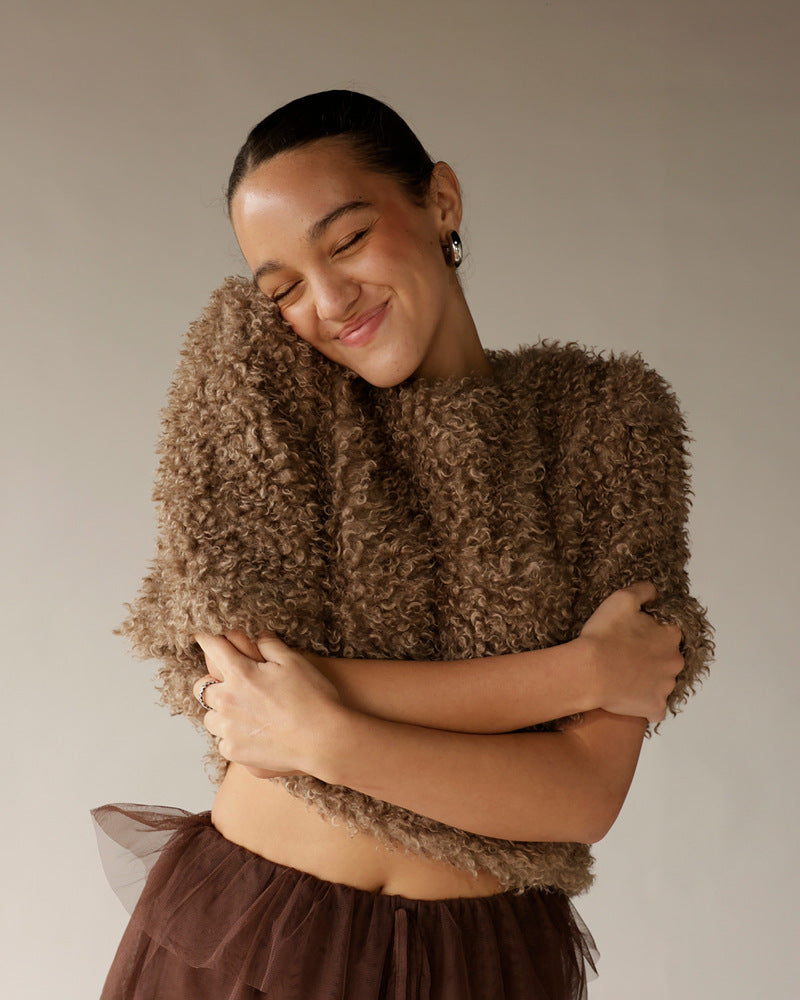 Woman hugging brown curly textured teddy sweater with structured shoulders