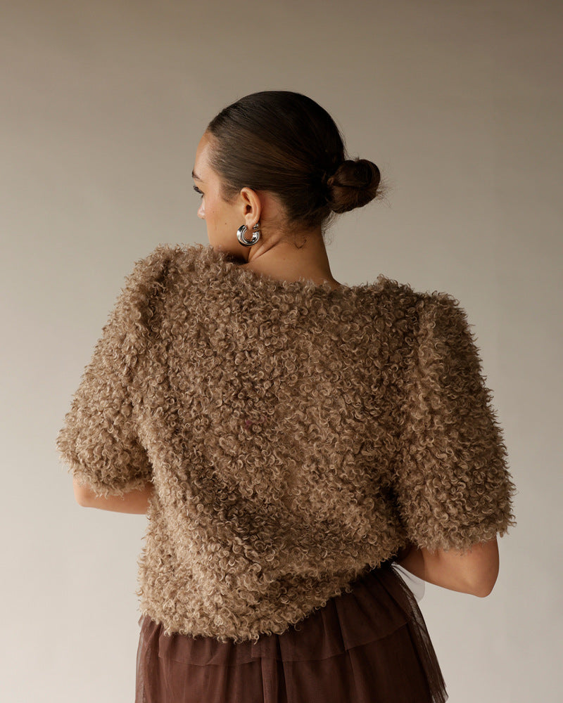Women's brown curly textured short-sleeve sweater, back view, worn with dark skirt