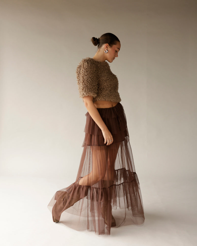 Women's brown curly textured crop sweater paired with sheer tiered maxi skirt
