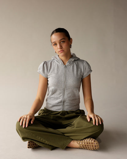Olive green cargo barrel pants, wide leg, worn with gray zip hoodie, cross-legged pose.